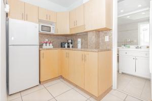 a kitchen with wooden cabinets and a white refrigerator at Girasole Rentals Suites in Miami Beach
