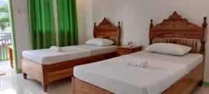 2 Betten in einem Zimmer mit grünen Vorhängen in der Unterkunft Casa Santuaria in Itaytay