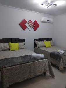 1 dormitorio con 2 camas con almohadas amarillas y rojas en Hospedagem Encantos da Serra en Itatiaia