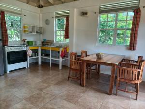 eine Küche mit einem Holztisch und Stühlen sowie einem Tisch und einem Herd in der Unterkunft Mango Garden Cottages in Tanetane