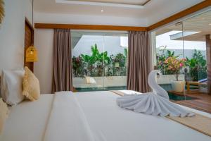 Un dormitorio con una cama blanca con un cisne. en Villa Ryky 2-bedroom private luxury villa in Nyanyi Beach, en Tanah Lot