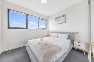 a white bedroom with a bed and two windows at Sydney Homebush Two bedroom Apartment with 2 Parkings in Sydney