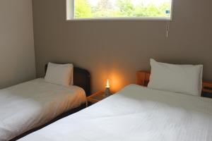 2 Betten in einem kleinen Zimmer mit Fenster in der Unterkunft IZUMIYA2 in Shin-karuisawa