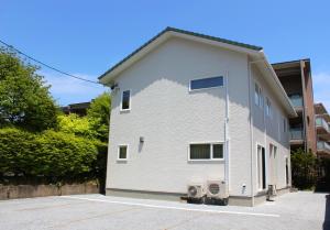 ein weißes Gebäude mit zwei Klimaanlagen in der Unterkunft IZUMIYA2 in Shin-karuisawa