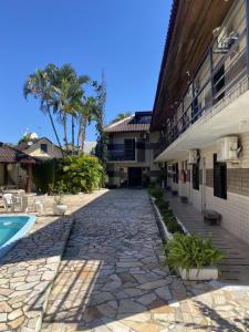 una pasarela de piedra junto a un edificio con piscina en Pousada Volare en Matinhos