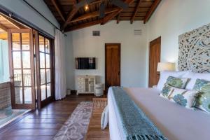 House of Dreams-5 Bedroom Home at Las Catalinas في Playa Danta: غرفة نوم بسرير ابيض كبير وتلفزيون