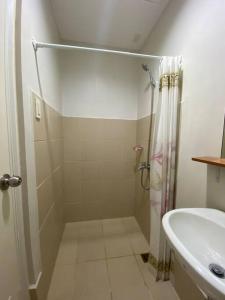 een witte badkamer met een douche en een wastafel bij Eve's Condo in Cagayan de Oro