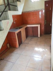 an empty kitchen with wooden cabinets and a tile floor at banyu urip kidul regency in Surabaya