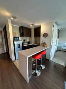 a kitchen with a counter and two red bar stools at Cómodo departamento 1D+1B in Los Ángeles