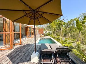 a patio with an umbrella and chairs and a pool at Nowhere Villa Uluwatu in Uluwatu