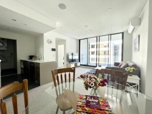 een keuken en een woonkamer met een glazen tafel en stoelen bij Spacious cozy2BR close to OlympicPark free carpark in Sydney