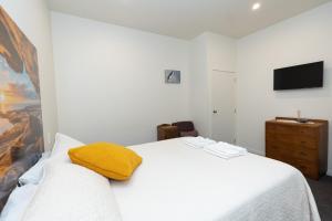 a bedroom with a white bed with a yellow towel on it at Tui Lodge Oakura 