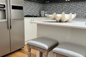 a kitchen with a counter with stools and a refrigerator at 6A Hough Street - pet friendly, air con, wi-fi and linen provided in Nelson Bay