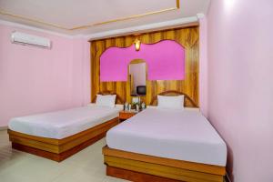a bedroom with two beds and a mirror at OYO Hotel C K International in Bodh Gaya