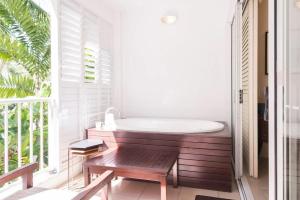 a bath tub sitting in a room with a window at Couple's Coastal Haven Retreat at The Beach Club in Palm Cove
