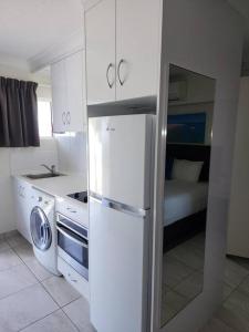 eine weiße Küche mit einem Kühlschrank und einem Bett in der Unterkunft Deluxe Studio - Unit 12 in Emu Park