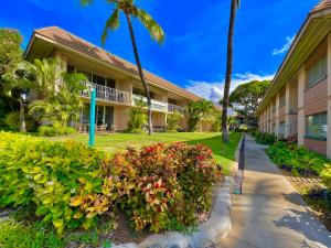a building with palm trees and a sidewalk at Kihei Kai Nani 368 in Kihei