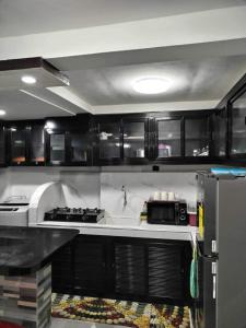 eine Küche mit schwarzen Schränken, einer Spüle und einem Kühlschrank in der Unterkunft Mini Home Traveller’s Inn 