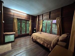 a bedroom with wooden walls and a bed and windows at Suchanaree@Laemngop in Trat