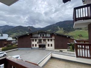 a building with a large parking lot with mountains in the background at Appartement Praz-sur-Arly, 2 pièces, 4 personnes - FR-1-603-83 in Praz-sur-Arly