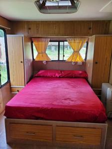 a bedroom with a red bed in a rv at Private Caravan and facilities - Tarzali Valley Veiws in Tarzali