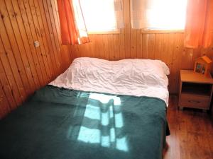 a small bed in a wooden room with a window at Bungalow with terrace, Wrzosowo in Wrzosowo