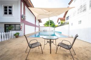 a table with two chairs and an umbrella next to a pool at The President Hotel at Chokchai 4 in Bangkok