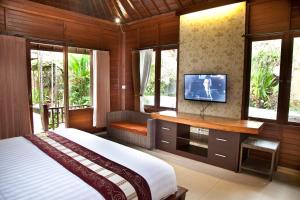 a bedroom with a bed and a tv and windows at Jepun Bali Hotel in Kuta