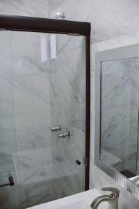 a bathroom with a shower with a mirror and a sink at Macfarland Suites in Ensenada +8 photos