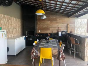 a kitchen with a table and some yellow chairs at LINDA CASA BARRA DE JACUIPE 8/4 ACOMODA ATE 20 PESSOAS in Camaçari