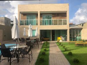 a house with a patio with tables and umbrellas at LINDA CASA BARRA DE JACUIPE 8/4 ACOMODA ATE 20 PESSOAS in Camaçari