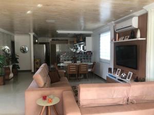 a living room with a couch and a television at LINDA CASA BARRA DE JACUIPE 8/4 ACOMODA ATE 20 PESSOAS in Camaçari