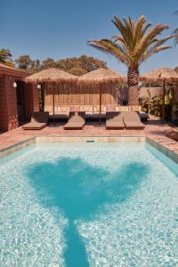una piscina con sedie e ombrelloni in un resort di Swell Hotel Byron Bay - Adults Only a Byron Bay