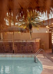 una piscina con un bar con sillas y una palmera en Swell Hotel Byron Bay - Adults Only, en Byron Bay