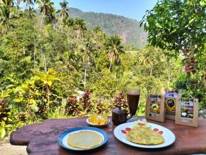 a table with plates of food and a glass of beer at Ananda Homestay Lemukih in Singaraja