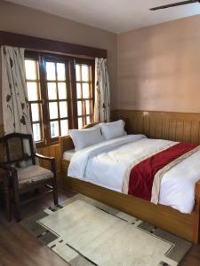 a bedroom with a bed and a chair and windows at Boudha Dungkar guest house in Kathmandu