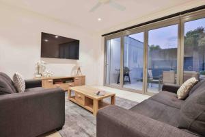 a living room with two couches and a table at Inner City Stay Mildura in Mildura