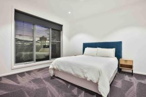 a bedroom with a large bed and a large window at Inner City Stay Mildura in Mildura