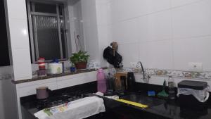a man standing in a kitchen next to a sink at Apartamento para temporada Ambiente familiar in Santos