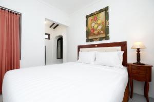 una camera con letto bianco e tavolo con lampada di Perdana Kasih Hotel Klaten a Solo