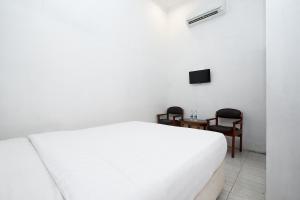 una camera con un letto bianco e due sedie di Perdana Kasih Hotel Klaten a Solo