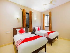 um quarto com 2 camas com almofadas vermelhas e brancas em Hotel Famy Palace em Udalguri