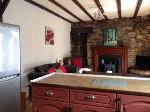 a kitchen with a living room with a fireplace at Darroch View Cottage in Invermoriston