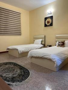 a bedroom with two beds and a clock on the wall at Italian House in Baghdād