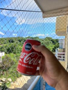 una persona sosteniendo una lata de coca frente a una ventana en Apartamentos de lujo puerto Colombia el encanto, en Puerto Colombia