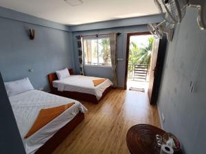 ロン島にあるRoomy Guesthouseのベッド2台と窓が備わる客室です。