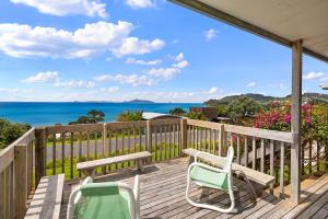une terrasse avec des chaises et un banc donnant sur l'océan dans l'établissement Bay View Bach - Langs Beach Holiday Home, à Waipu