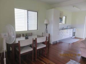 a living room with a table and chairs and a kitchen at Emu Park Beach Front Apartment in Emu Park