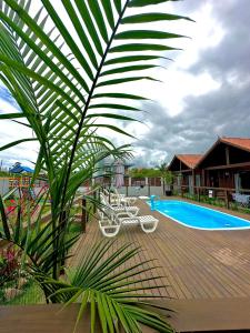 una terraza con sillas y una piscina en POUSADA ROSA e POESIA en Praia do Rosa