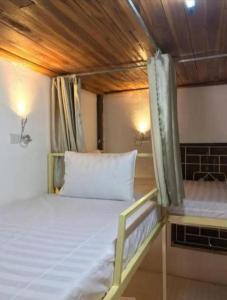 a bed in a room with a wooden ceiling at Watthat & Maladreds GUESTHOUSE dorm 1 in Luang Prabang